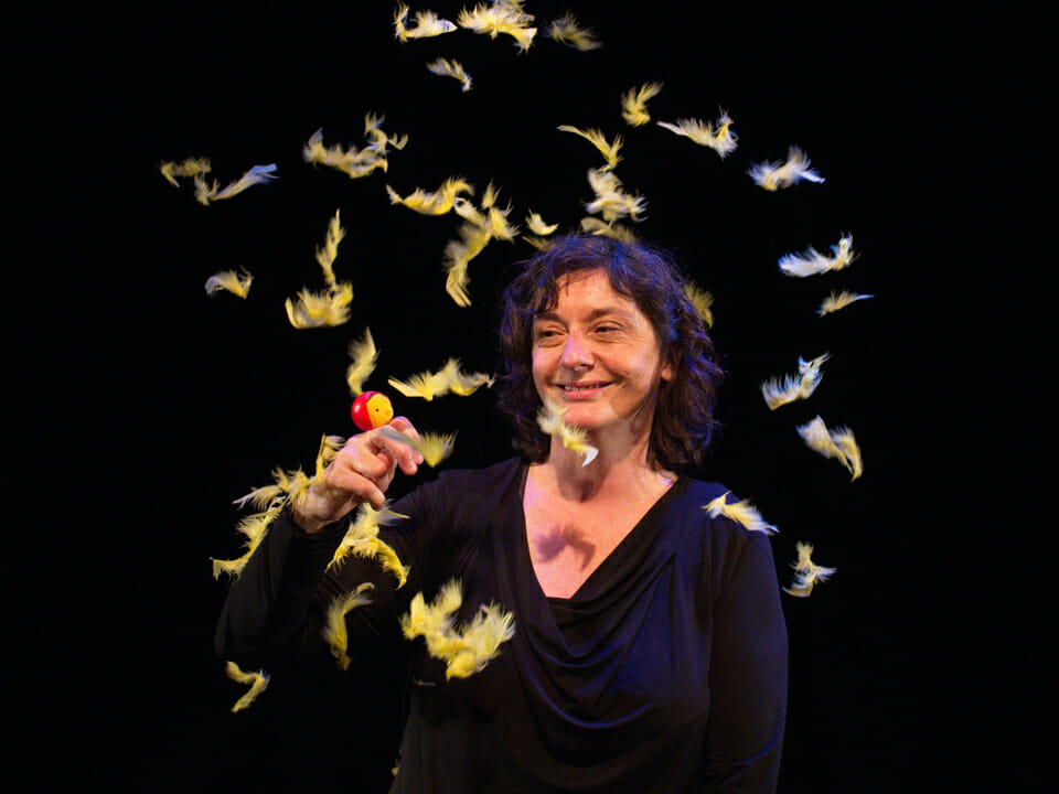 Une dame joue avec une marionnette et des plumes jaunes