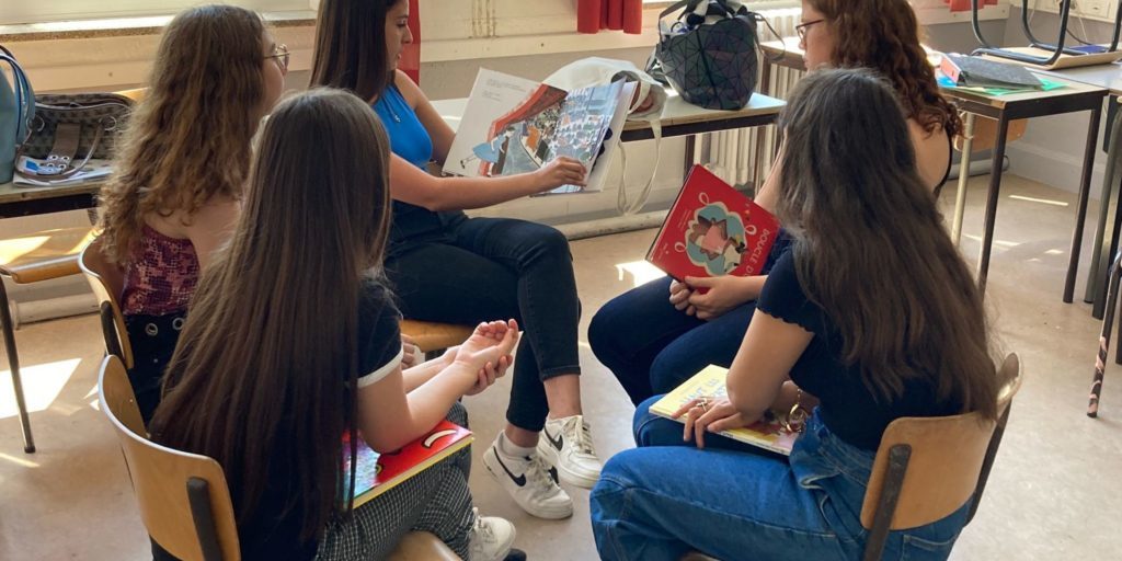 Des adolescents ont assis en cercle et apprennent à lire des livres aux plus-petits.